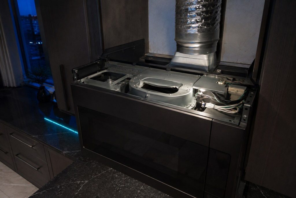 The blower housing inside the top of an over-the-range microwave with its vent flap turned
