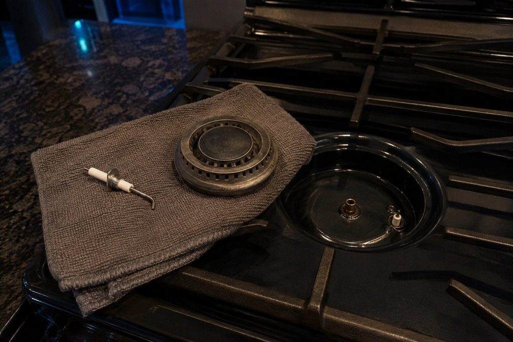 A spark igniter and a burner head lying apart on a folded towel beside the empty burner base